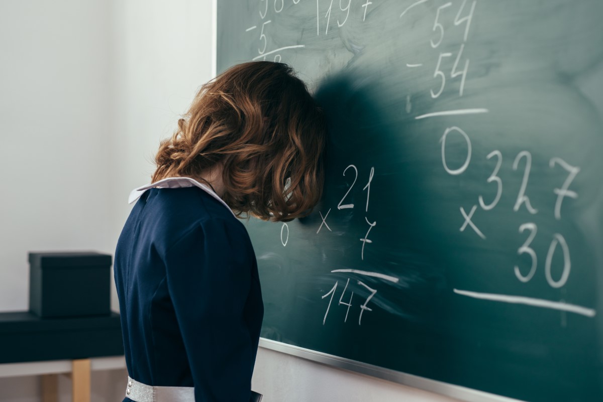 Student puts her head on the chalk board in frustration.